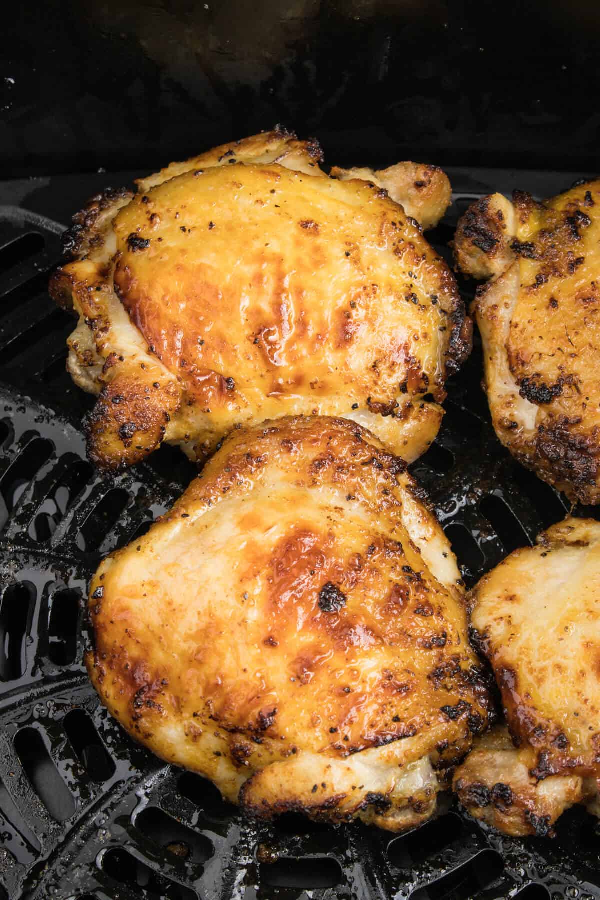 Lemon chicken thighs cooked in an air fryer basket.