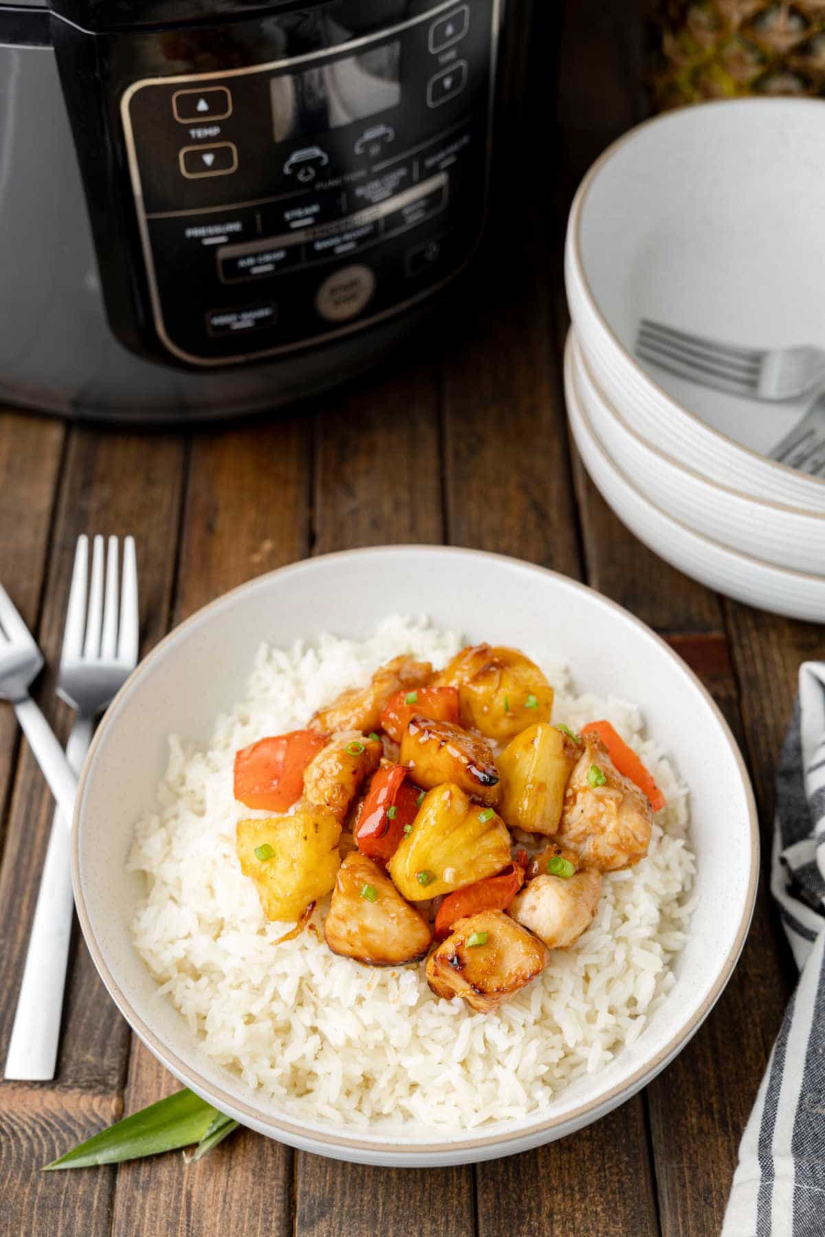 Pineapple chicken on a bed of rice in a bowl.