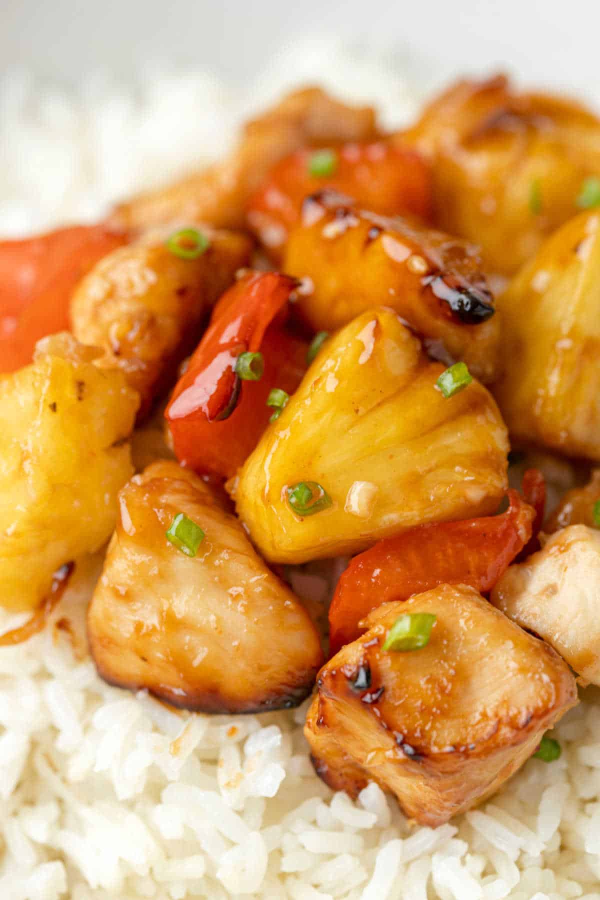 Close up of pineapple chicken on a bed of rice in a bowl.