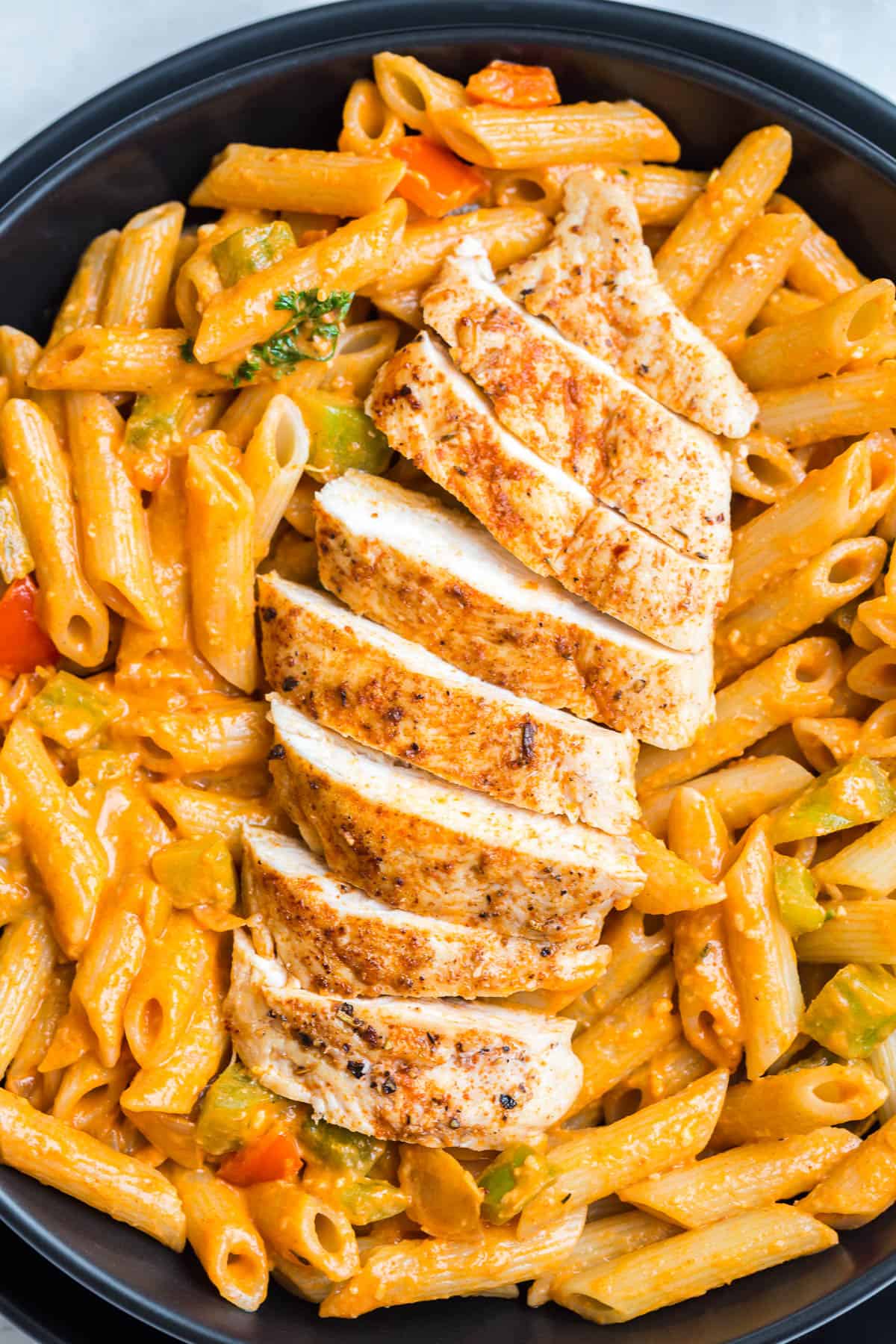 close up of slicked cajun chicken breasts over a creamy tomato sauce