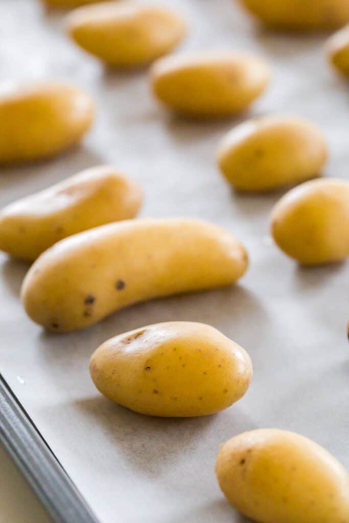 laying the potatoes on a sheet pan lined with parchment paper