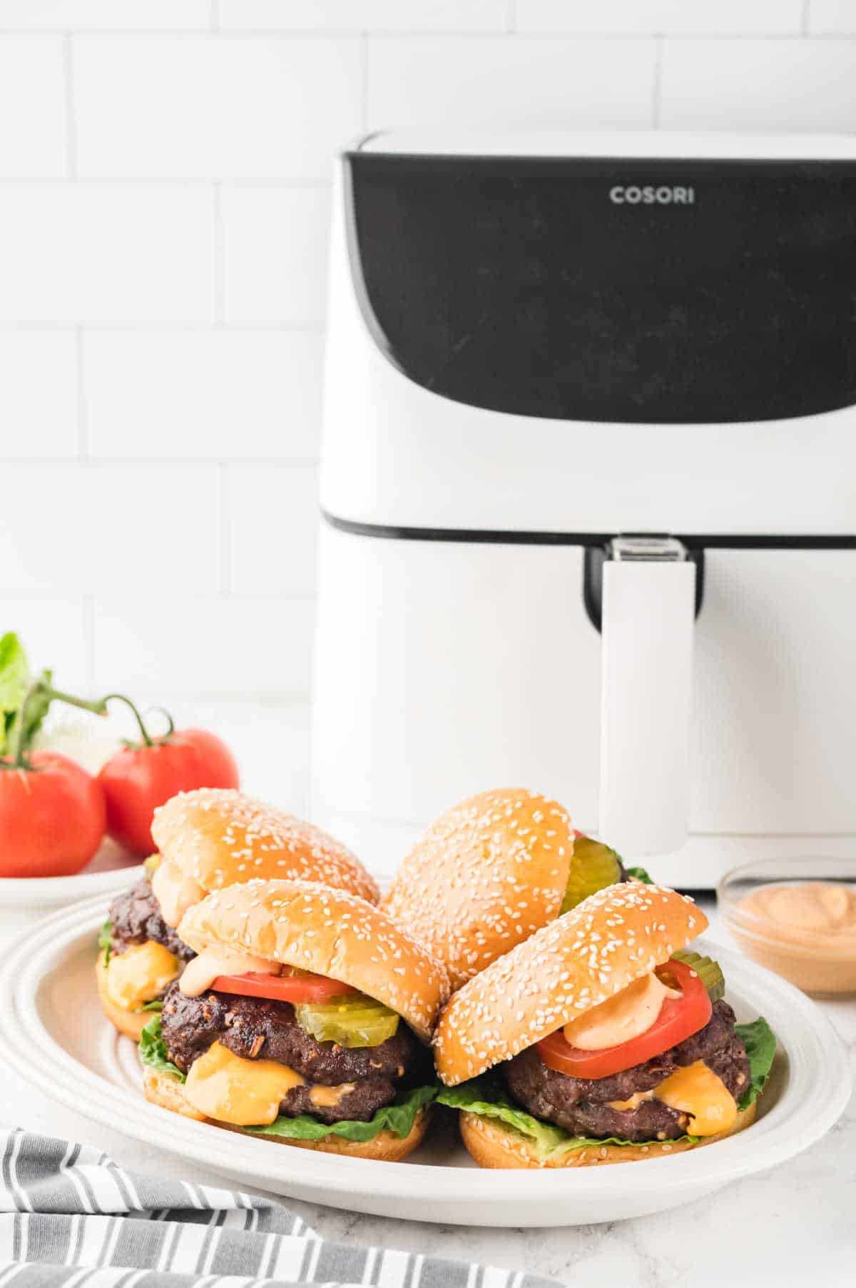 Juicy lucy burgers on a plate in front of a white air fryer.
