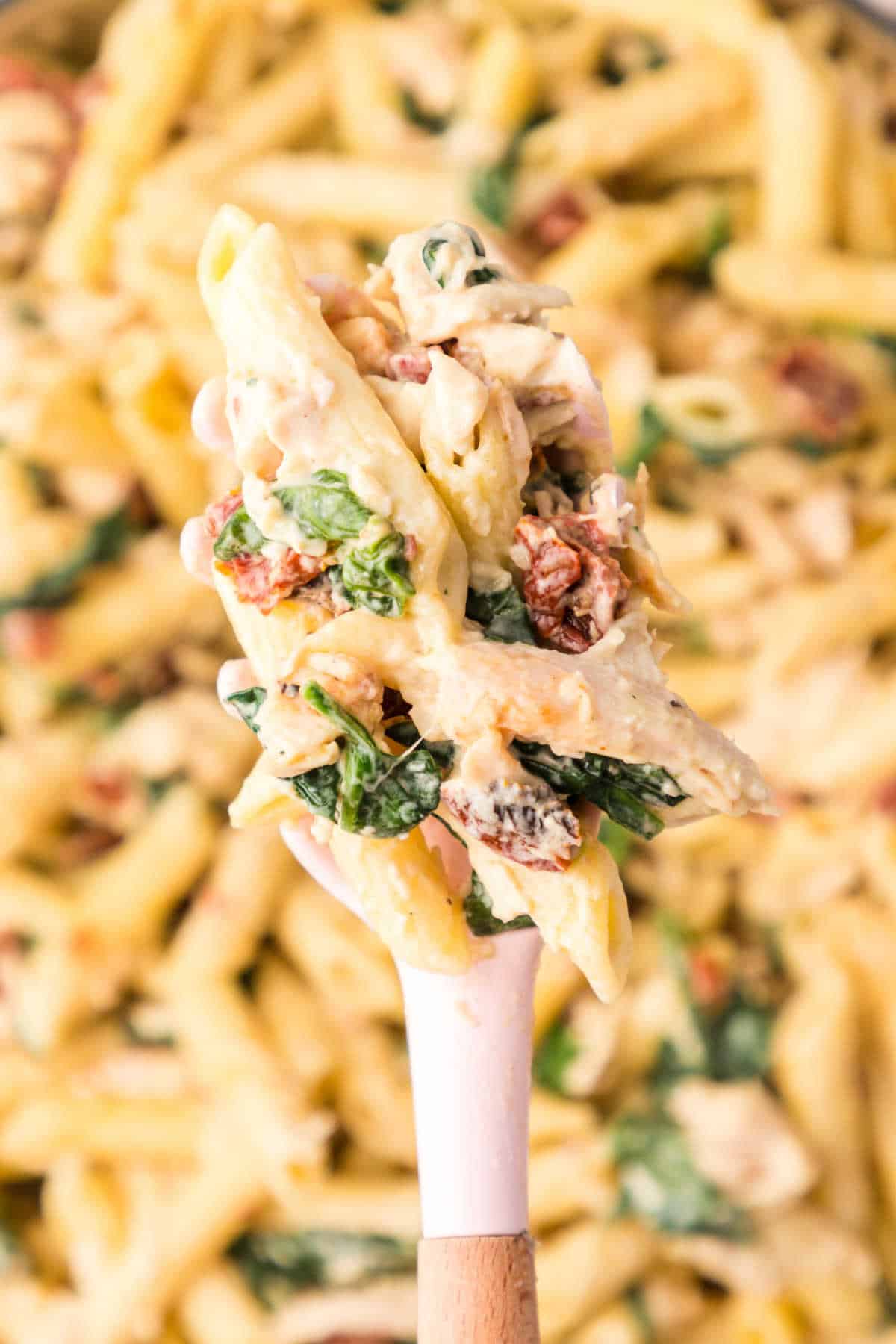 Chicken and spinach pasta on a serving spoon.