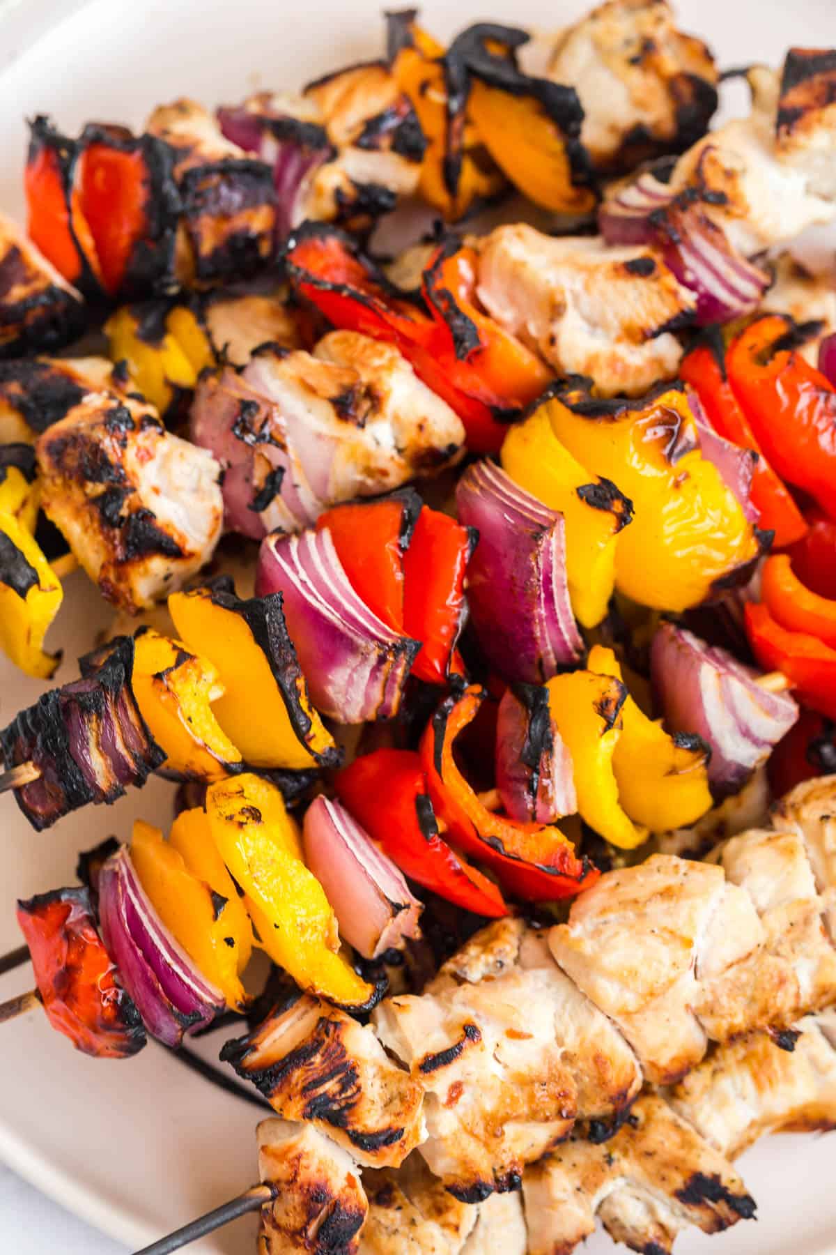 close up of charred chicken and peppers on a wooden skewer