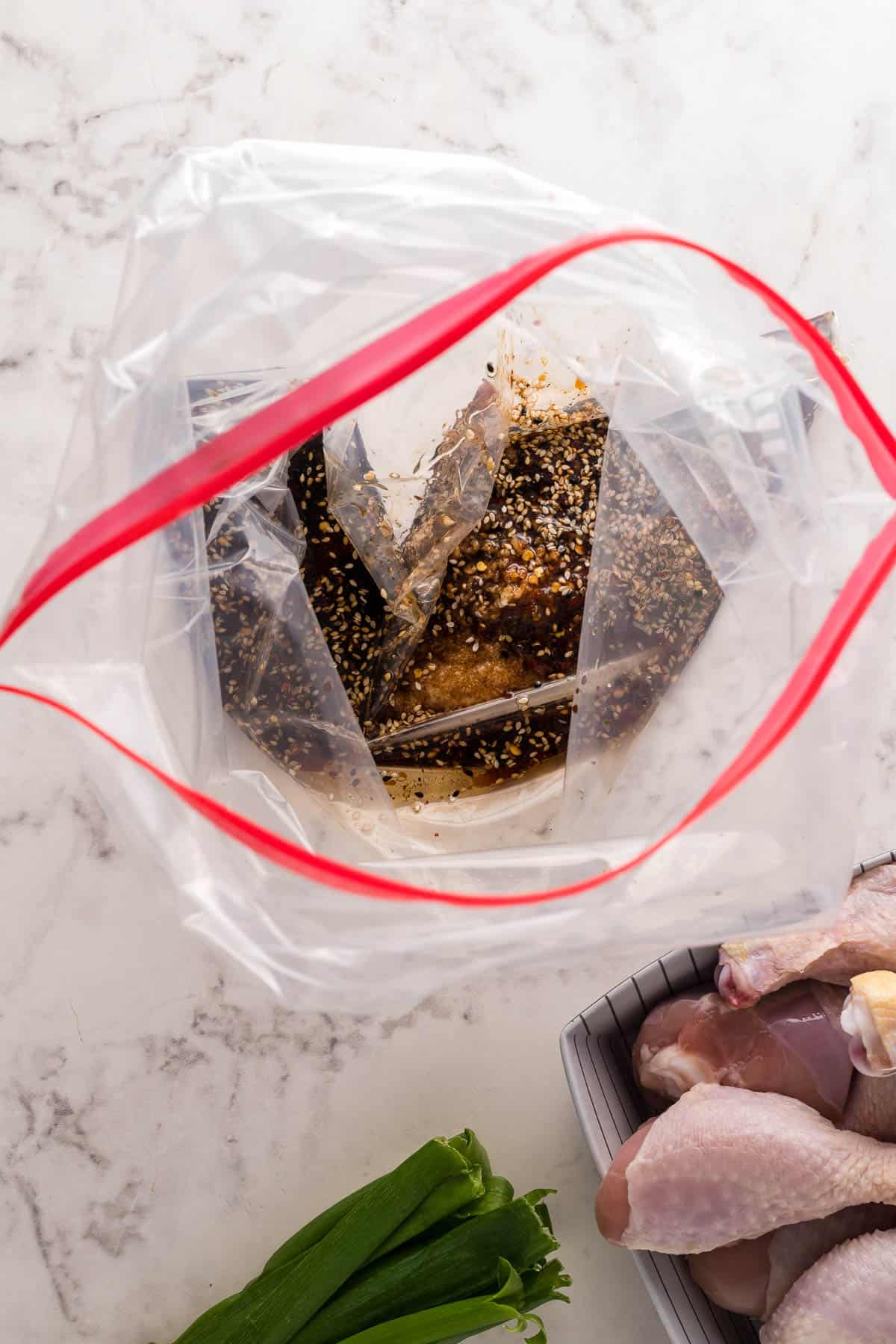 adding a homemade asian sesame marinade to a ziploc bag over chicken