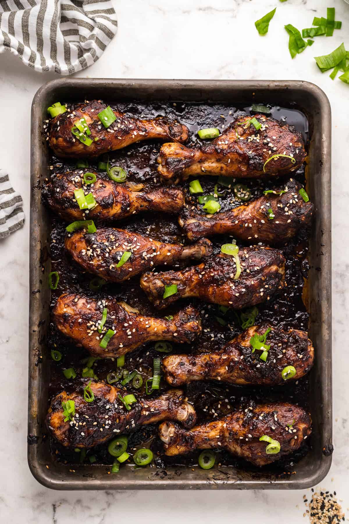 sesame chicken drumsticks on a sheet pan with green onions
