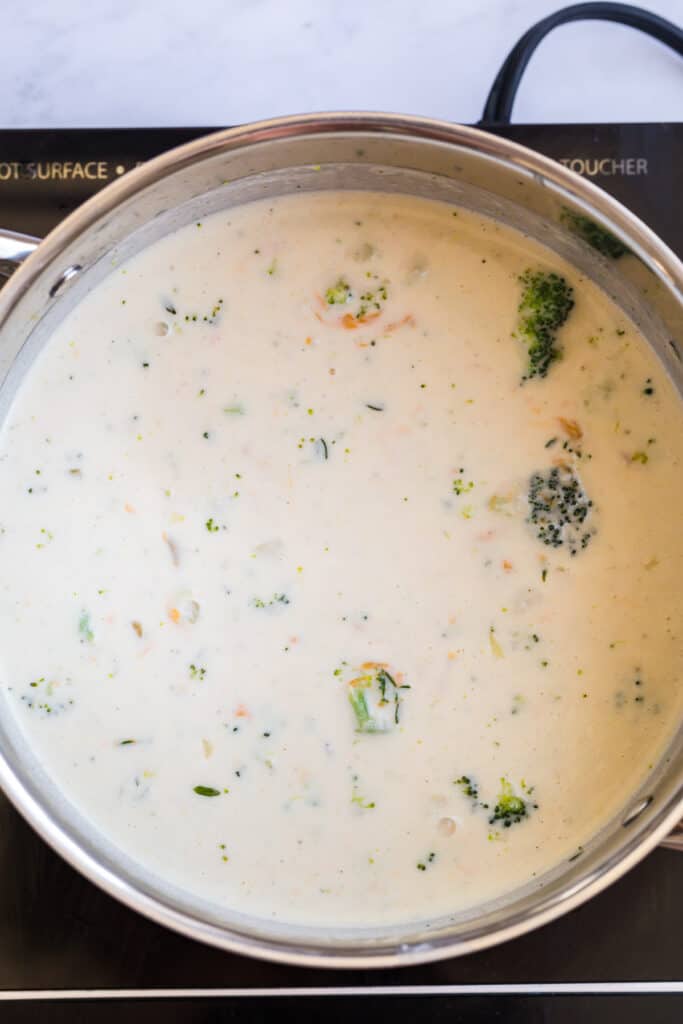 creamy broccoli soup melting the cheese over the burner