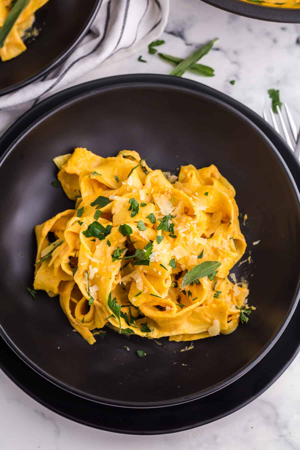overview of thick pasta noodles with a creamy pumpkin sauce topped with fresh parmesan and sage