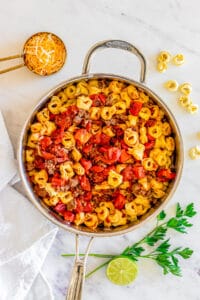 adding cooked tortellini to a skillet with ground beef and tomatoes