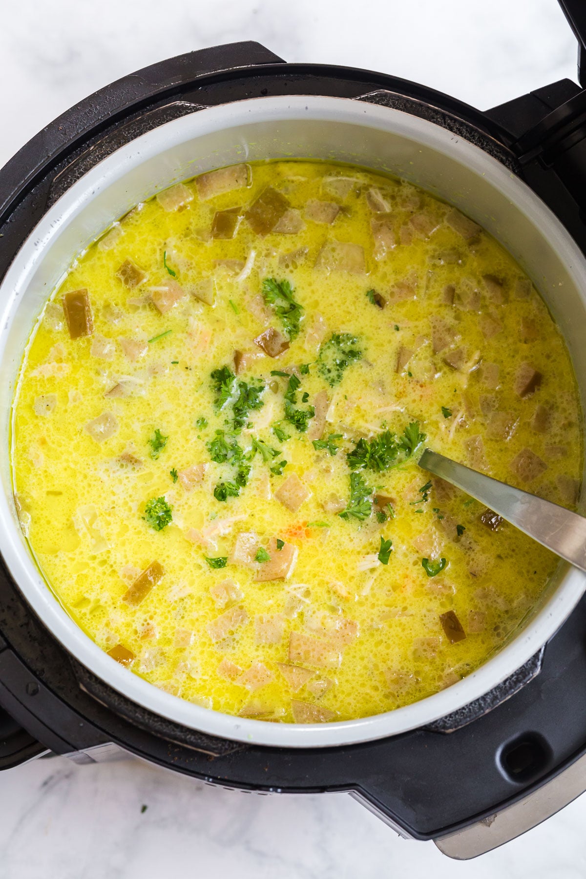 Slow cooker mulligatawny soup in the slow cooker, garnished with fresh parsley.